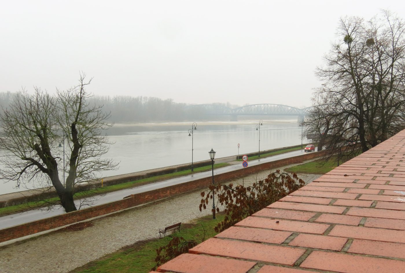 The Wisła seen from the brick town wall in Toruń, with the embankment road and the steel road bridge in the mist